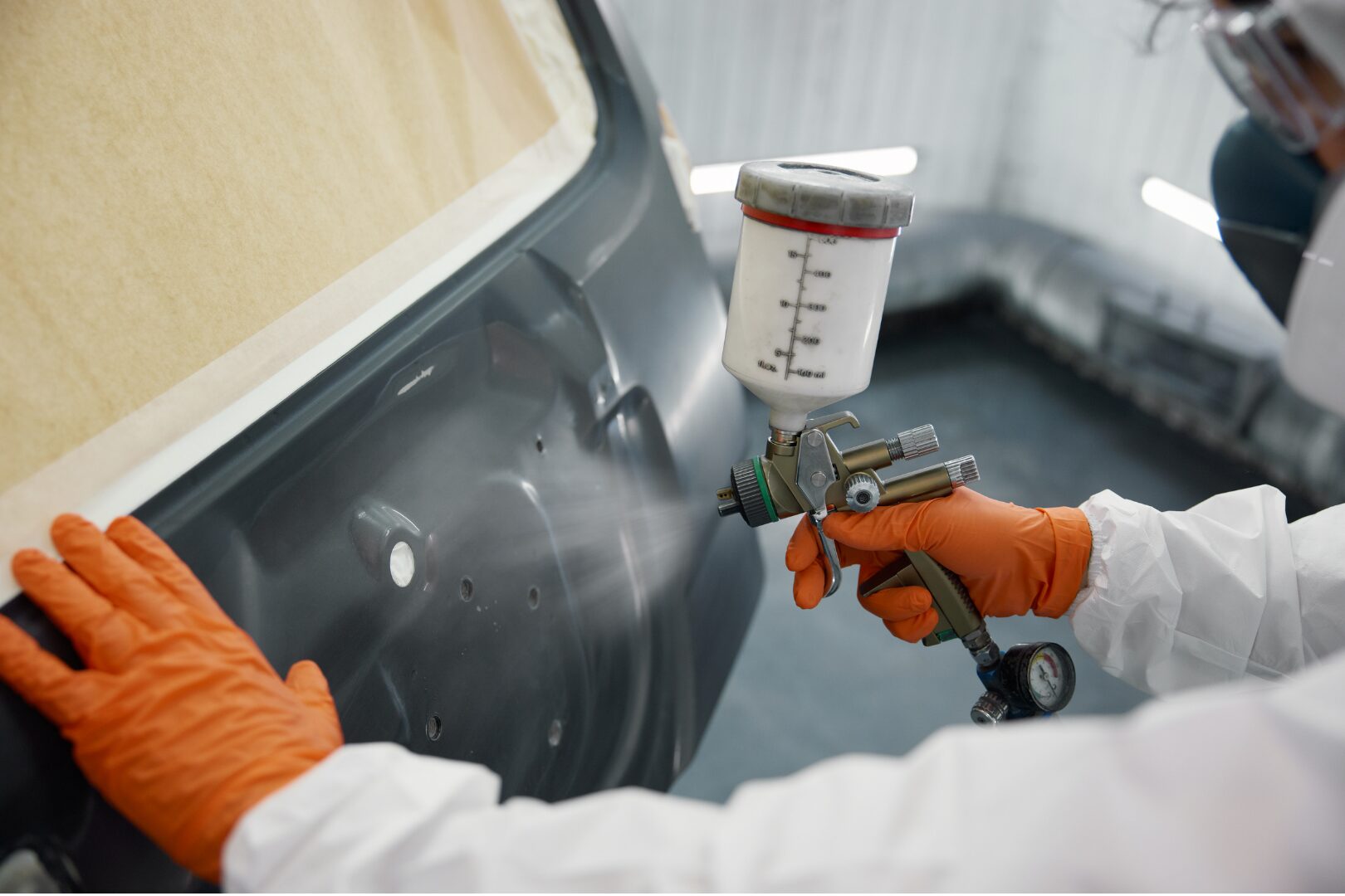 Technician respraying a car after multiple dents were repaired.