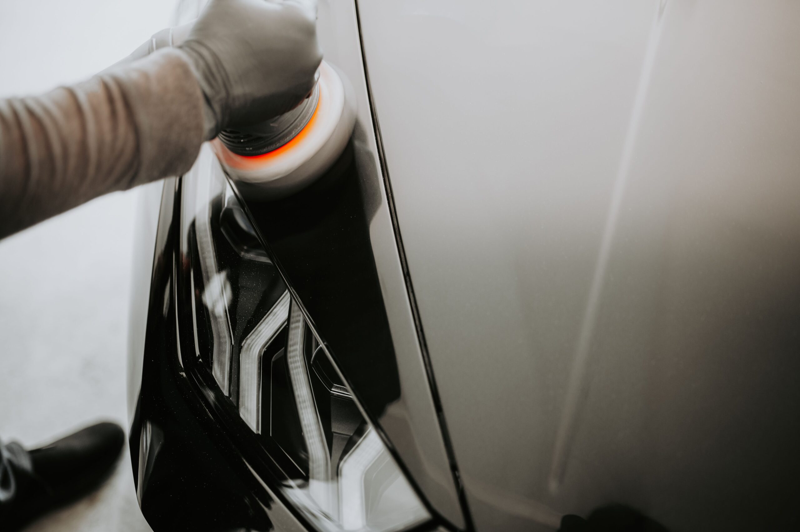 Technician using a machine polisher for professional paint correction on a car.