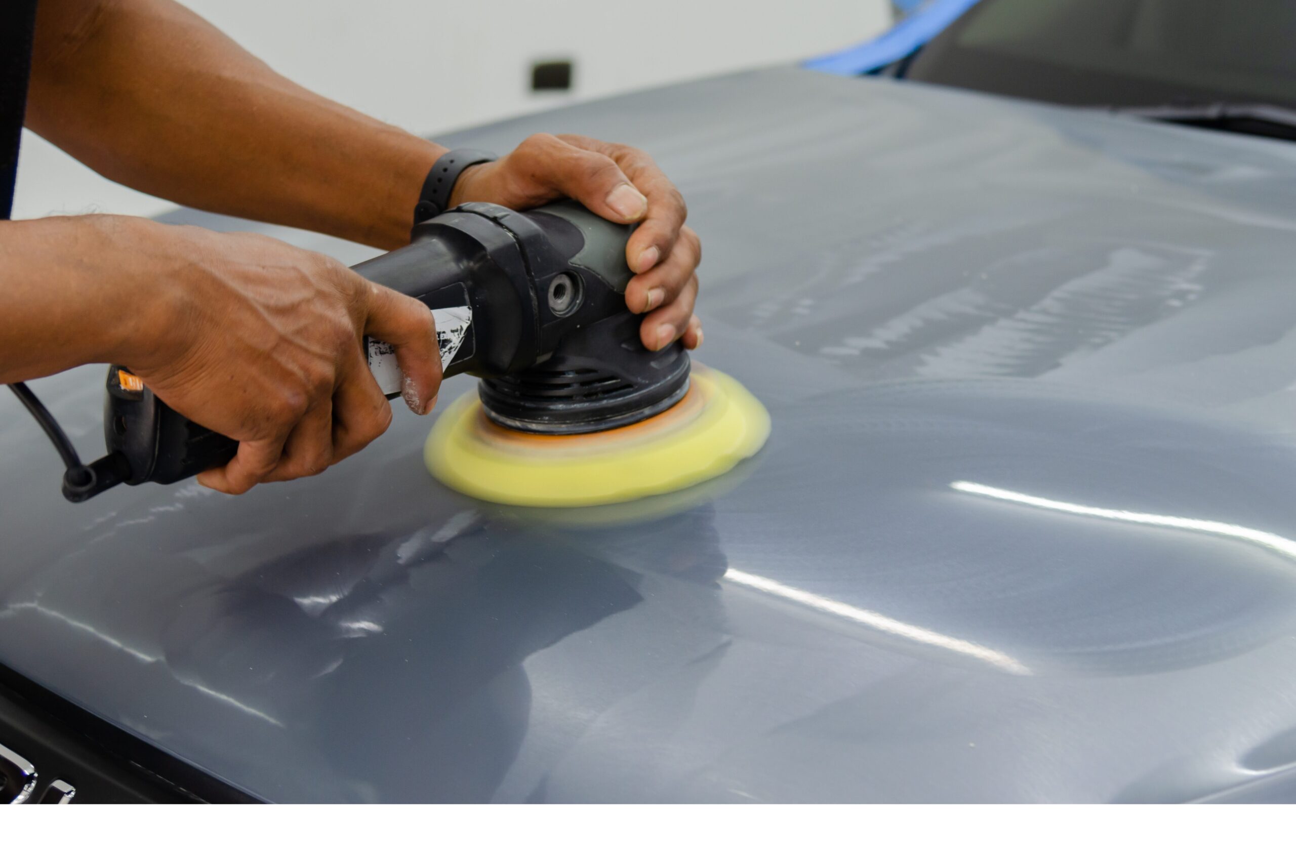 Panel beater buffing out a scratch with a machine polisher.
