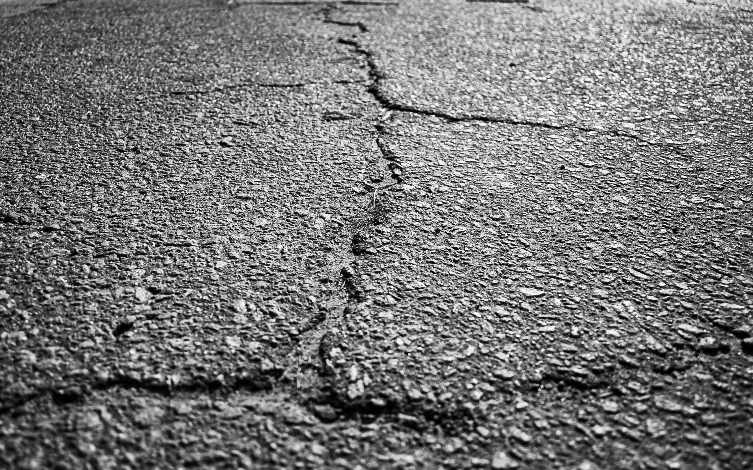 Cracked asphalt and loose gravel road surface.