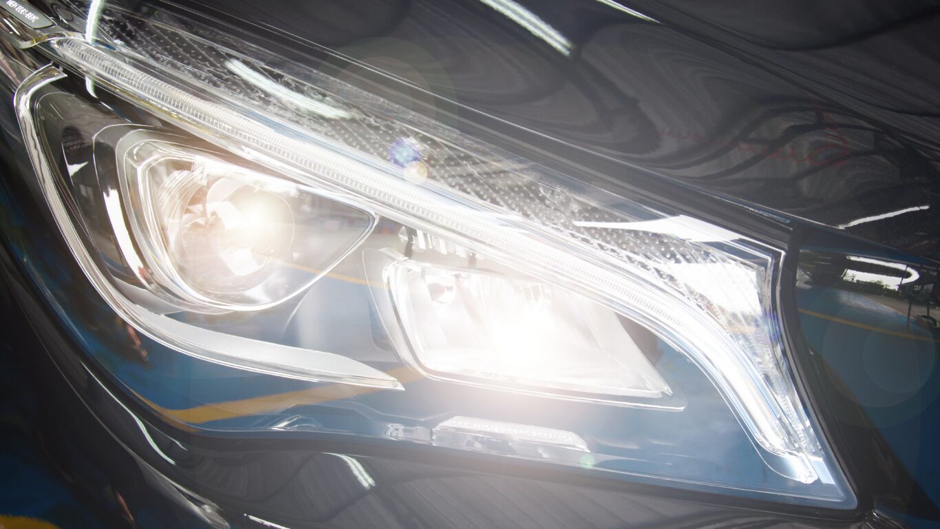Clear, restored car headlamp shining brightly after pre-trip automotive repair checks for safer night driving on a December road trip.