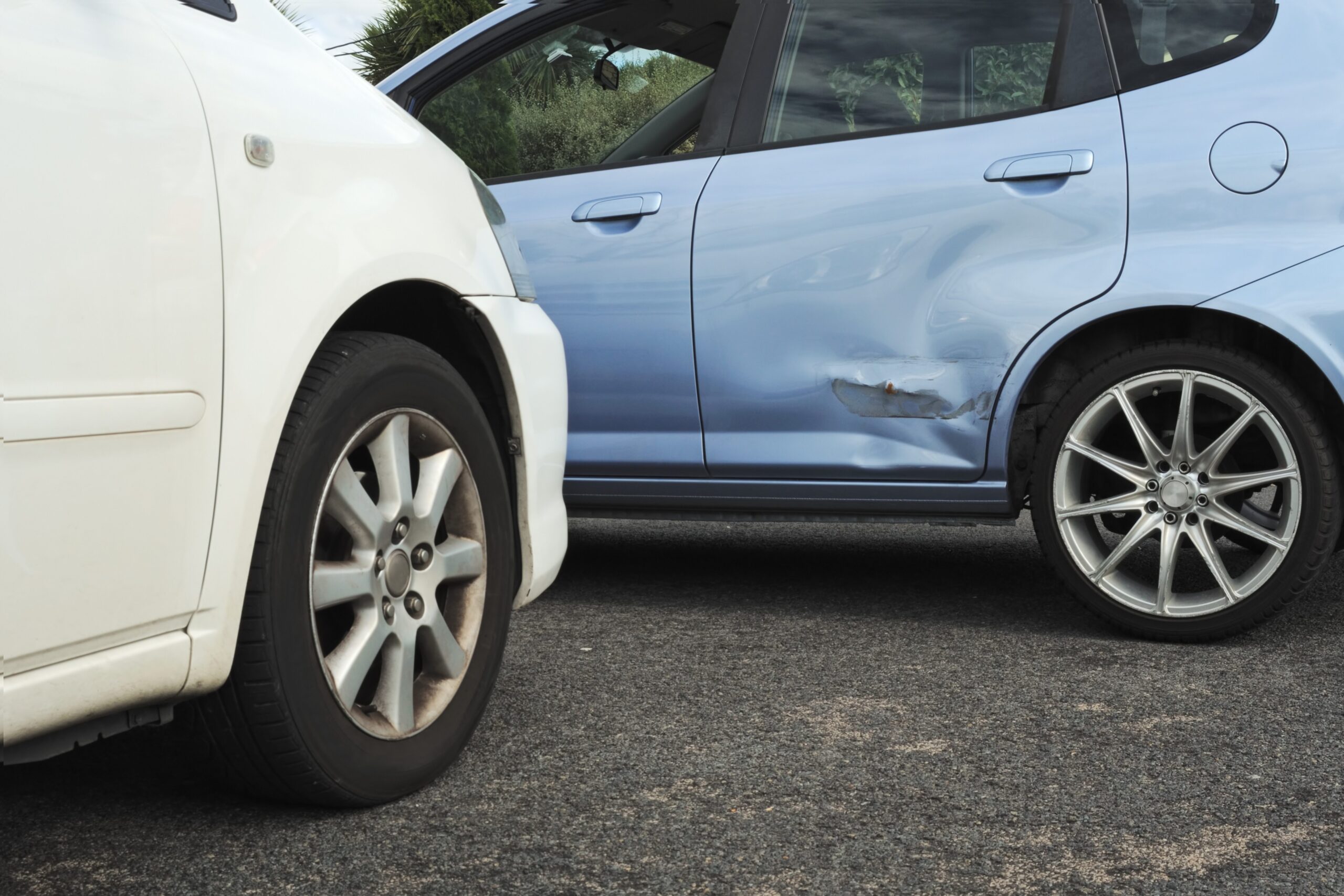 Dent repair near me needed after a minor car accident, with a white car denting a blue car’s rear door.