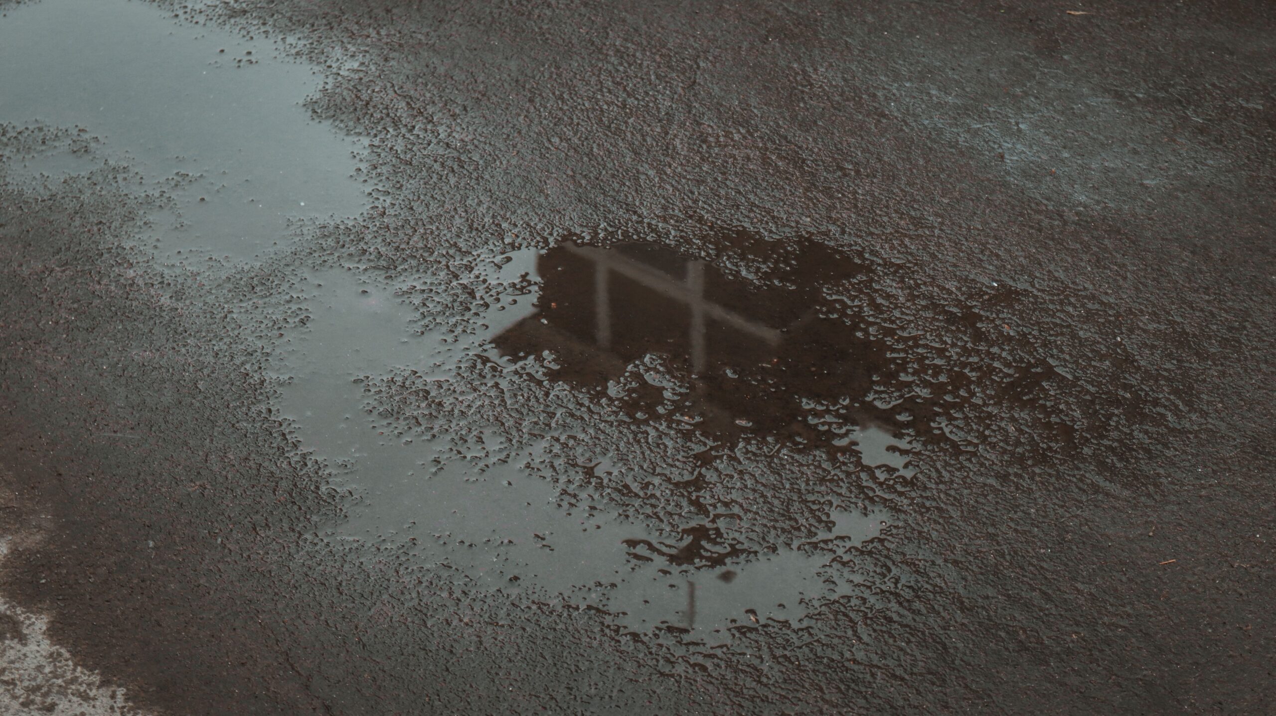 Panel beater near me for pothole damage repairs in Johannesburg: rain-filled pothole on a wet road surface.